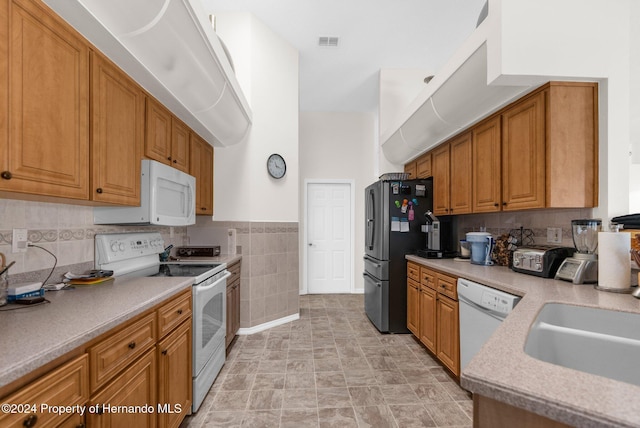 8016 Bellevista Ct, Spring Hill, FL 34606 - kitchen featuring white appliances, brown cabinets, light countertops, a sink, and tile walls