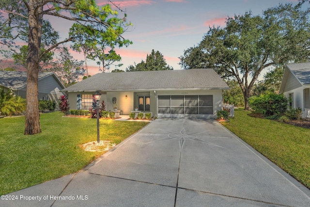 single story home featuring a garage and a yard