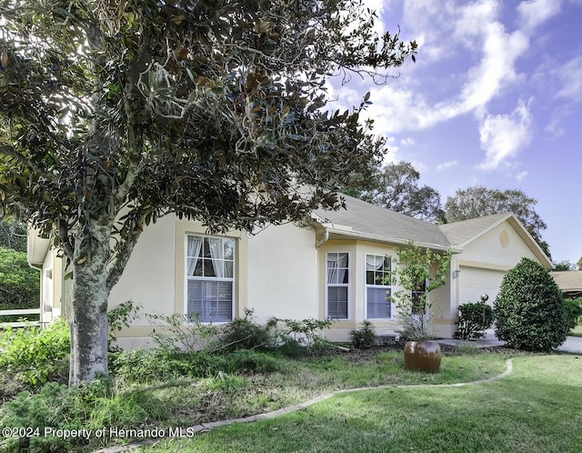 3472 Hartley Rd, Spring Hill, FL 34606 - view of property exterior featuring a garage, a lawn, and stucco siding