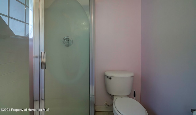 bathroom with toilet and a shower with door