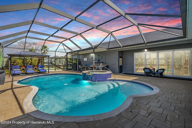 pool at dusk with a gazebo, glass enclosure, an in ground hot tub, and a patio area