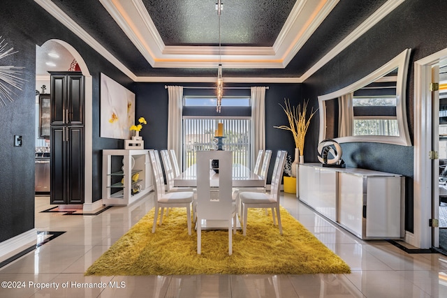 tiled dining room featuring a healthy amount of sunlight, a raised ceiling, and ornamental molding