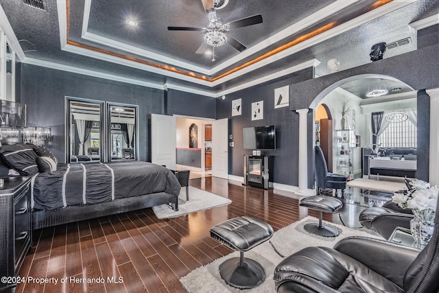 bedroom with ornate columns, a tray ceiling, ceiling fan, and dark hardwood / wood-style floors