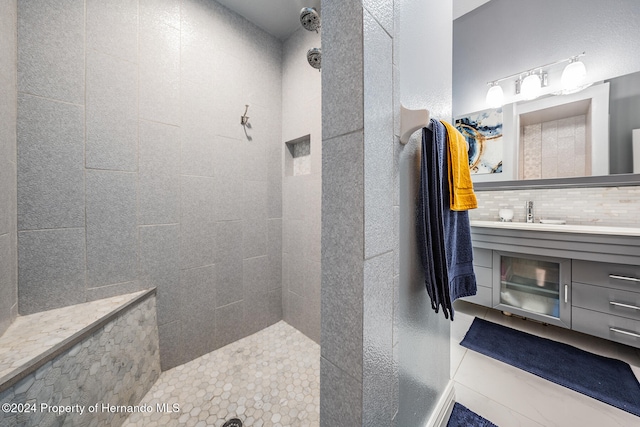 bathroom featuring decorative backsplash, tiled shower, tile patterned floors, and vanity