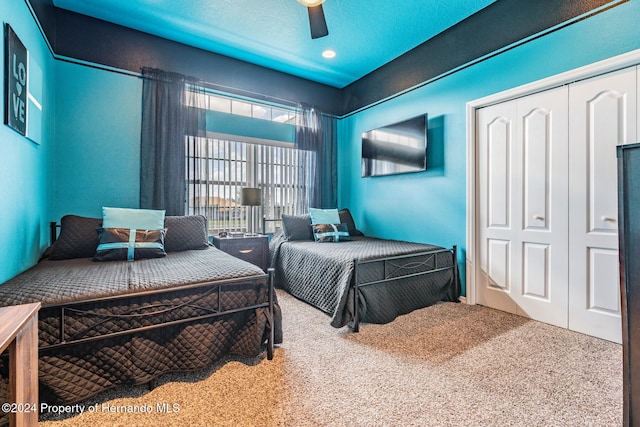 carpeted bedroom with ceiling fan, a textured ceiling, and a closet