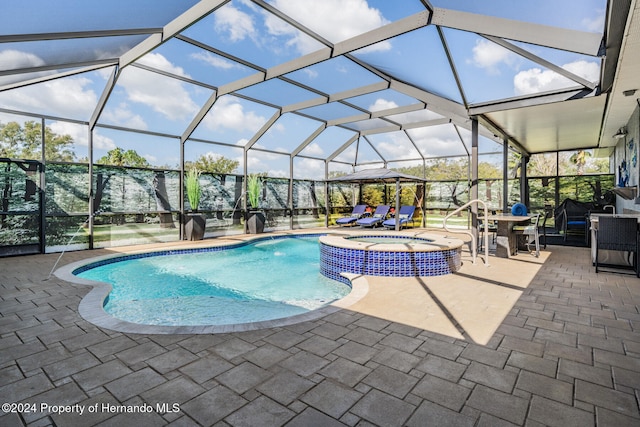 view of swimming pool with a patio, glass enclosure, and an in ground hot tub