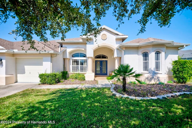 mediterranean / spanish-style house with a front yard, french doors, and a garage