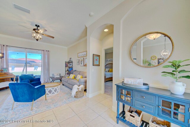 living room with light tile patterned floors, ceiling fan with notable chandelier, vaulted ceiling, and ornamental molding