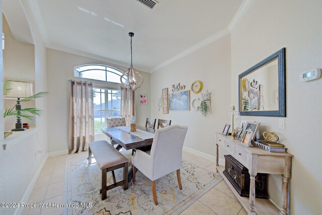 dining room featuring crown molding, light tile patterned flooring, and an inviting chandelier