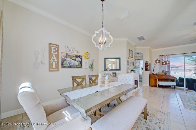 dining area featuring a notable chandelier, ornamental molding, and light tile patterned flooring