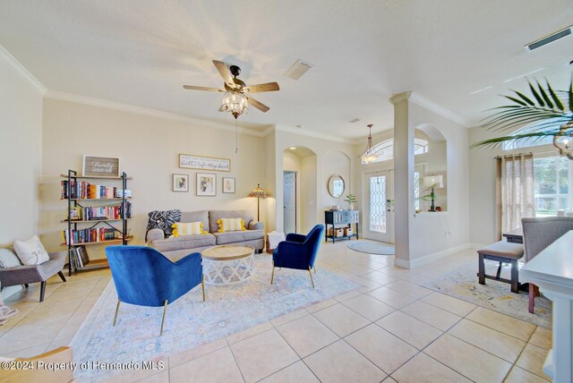 tiled living room with ceiling fan with notable chandelier and crown molding