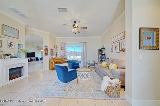 tiled living room with ceiling fan and ornamental molding