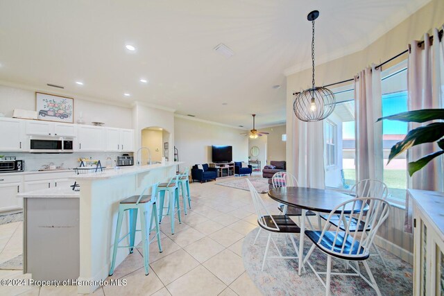 tiled dining room featuring ceiling fan and crown molding