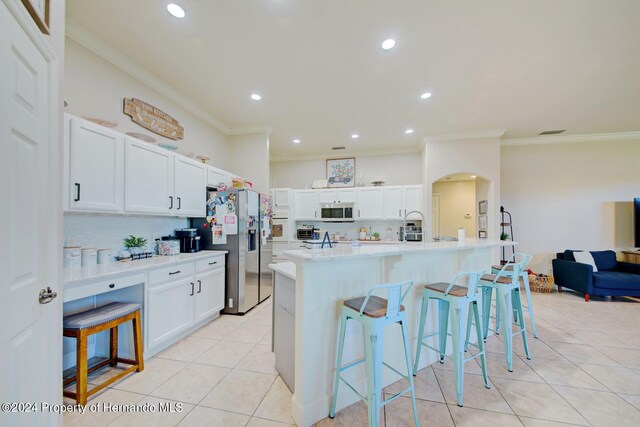 kitchen with a breakfast bar, white cabinetry, a kitchen island with sink, and stainless steel appliances