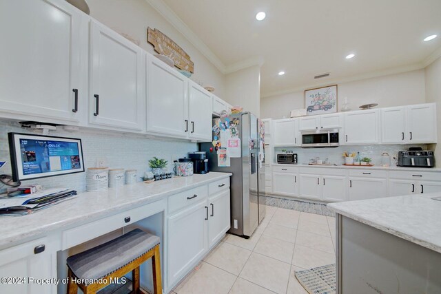 kitchen featuring appliances with stainless steel finishes, light stone counters, ornamental molding, white cabinetry, and light tile patterned flooring