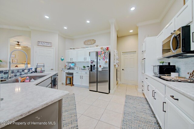 kitchen with ceiling fan, sink, stainless steel appliances, tasteful backsplash, and white cabinets