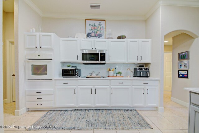 kitchen with white cabinets, backsplash, and white oven