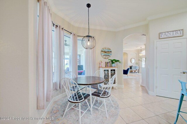 dining area featuring crown molding, light tile patterned floors, and a chandelier