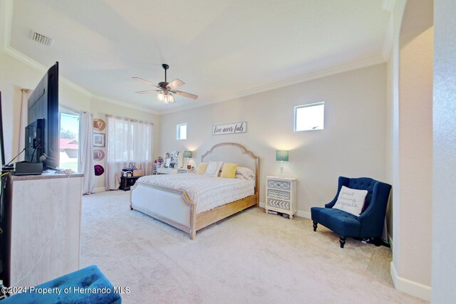 carpeted bedroom with multiple windows, ornamental molding, and ceiling fan