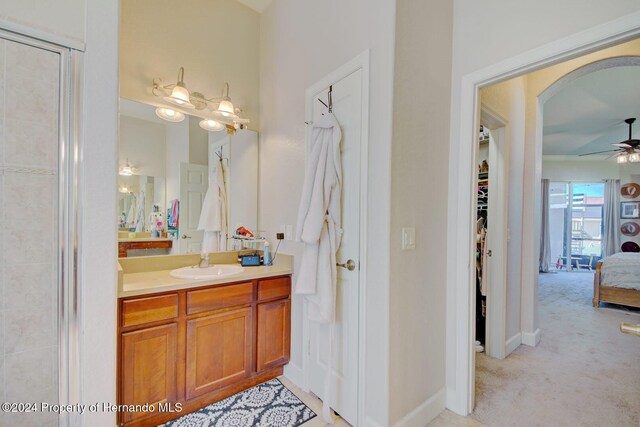 bathroom with vanity, a shower with door, and ceiling fan