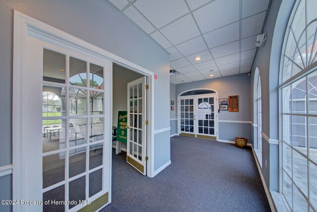 interior space featuring french doors, dark carpet, and a drop ceiling