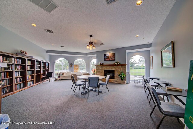 carpeted dining room featuring a healthy amount of sunlight, a textured ceiling, and a brick fireplace