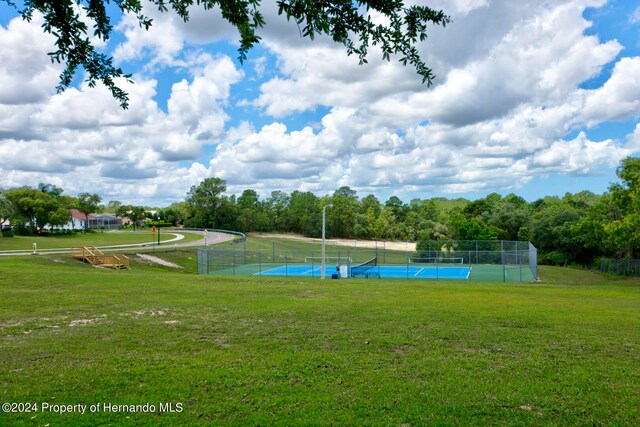 view of home's community with a lawn and tennis court