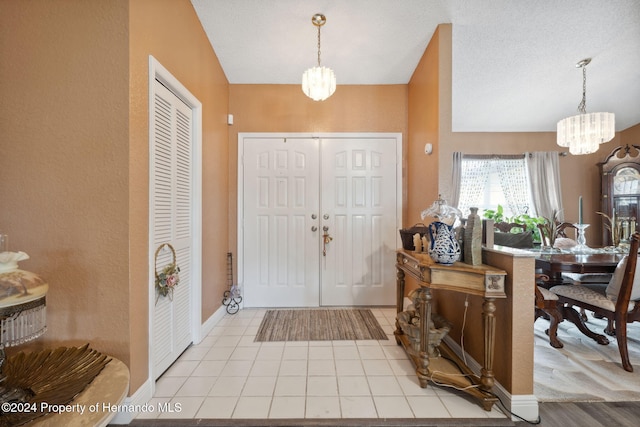 entrance foyer featuring light wood-type flooring, an inviting chandelier, and a textured ceiling