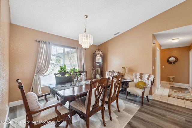 dining area with hardwood / wood-style floors, a chandelier, a textured ceiling, and lofted ceiling