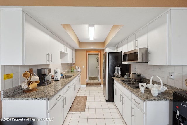 8227 Rhanbuoy Rd, Spring Hill, FL 34606 - kitchen with appliances with stainless steel finishes, light tile patterned floors, decorative backsplash, and white cabinetry
