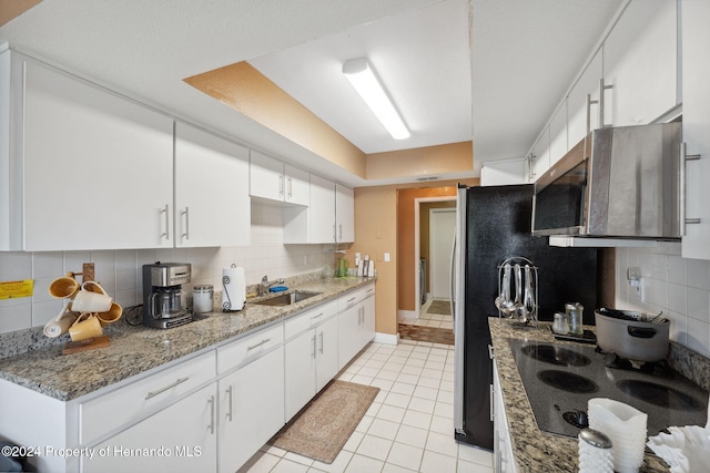 8227 Rhanbuoy Rd, Spring Hill, FL 34606 - kitchen featuring electric cooktop, stainless steel microwave, tasteful backsplash, and light tile patterned flooring