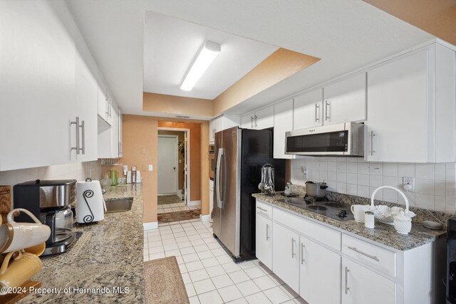 8227 Rhanbuoy Rd, Spring Hill, FL 34606 - kitchen with stainless steel appliances, light tile patterned flooring, tasteful backsplash, and white cabinets
