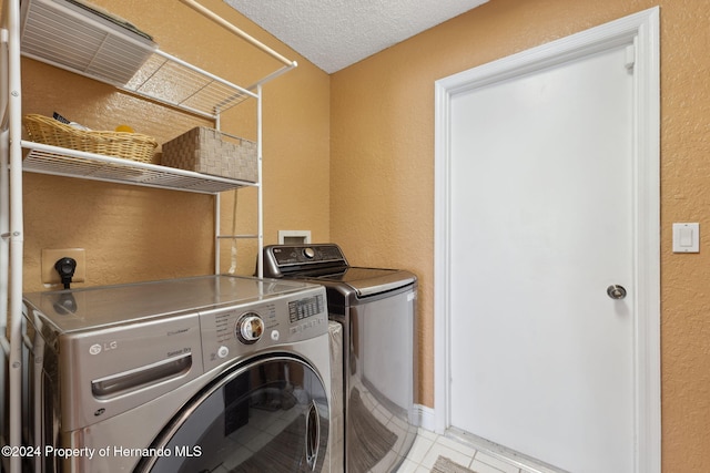 8227 Rhanbuoy Rd, Spring Hill, FL 34606 - laundry area with washer and clothes dryer, a textured wall, light tile patterned floors, and a textured ceiling