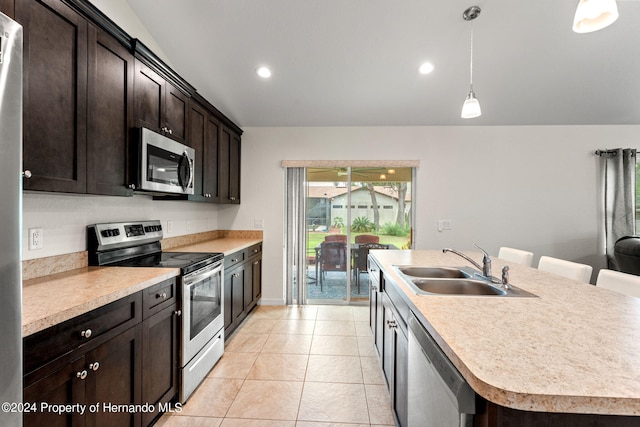 kitchen with lofted ceiling, a center island with sink, sink, pendant lighting, and appliances with stainless steel finishes