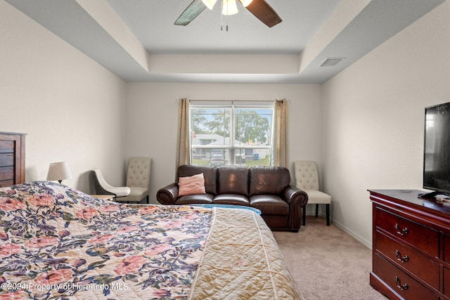 bedroom with light colored carpet, ceiling fan, and a tray ceiling