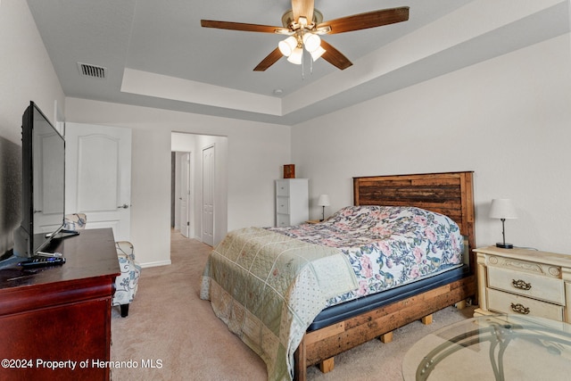 bedroom featuring light colored carpet, ceiling fan, and a raised ceiling