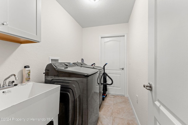 clothes washing area featuring cabinets, sink, a textured ceiling, light tile patterned floors, and independent washer and dryer