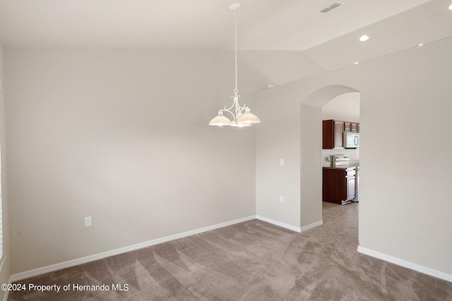 carpeted empty room featuring vaulted ceiling