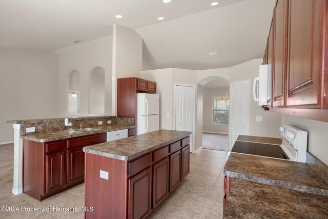 kitchen featuring a kitchen island, light tile patterned floors, vaulted ceiling, sink, and white appliances