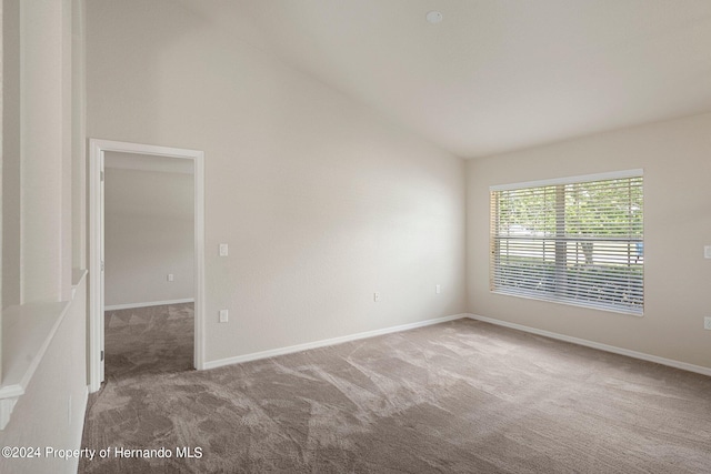 empty room featuring carpet and vaulted ceiling