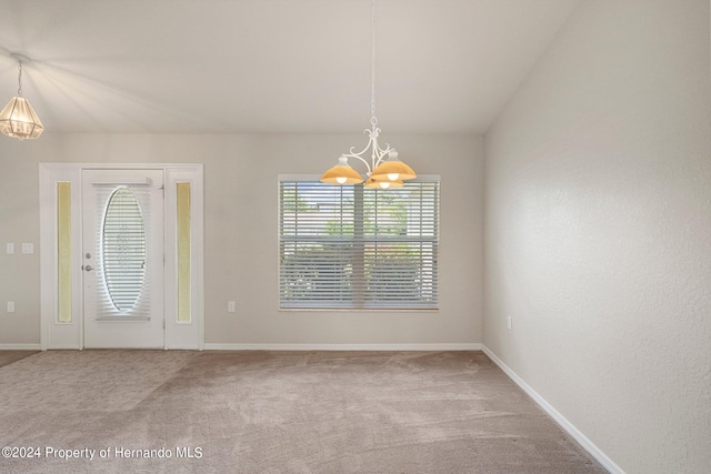 spare room with carpet flooring, lofted ceiling, and a notable chandelier