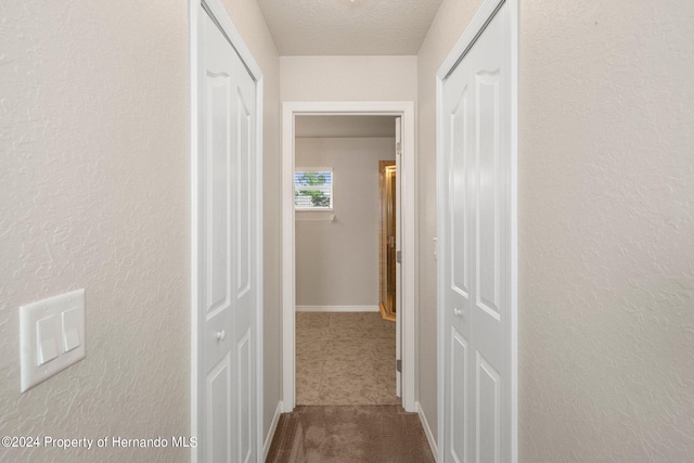 hallway featuring a textured ceiling and carpet floors