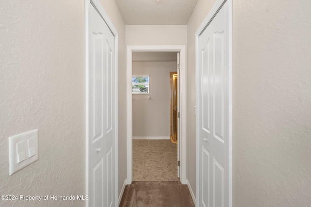 12161 Cavern Rd, Spring Hill, FL 34609 - hallway with dark carpet, a textured wall, and a textured ceiling