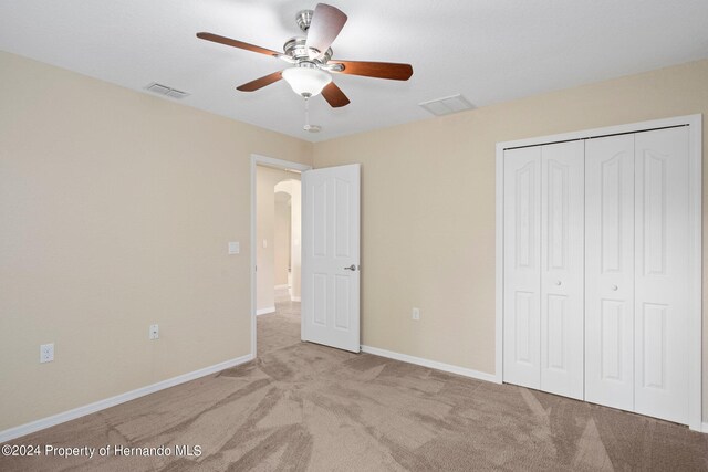 unfurnished bedroom with light colored carpet, ceiling fan, and a closet