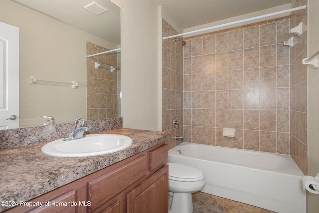 full bathroom with tile patterned floors, toilet, tiled shower / bath combo, a textured ceiling, and vanity