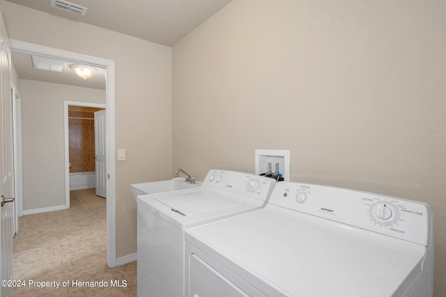 laundry area featuring light tile patterned floors, sink, and washing machine and clothes dryer