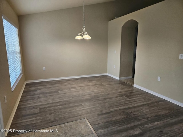 12161 Cavern Rd, Spring Hill, FL 34609 - empty room with arched walkways, plenty of natural light, dark wood finished floors, and a chandelier