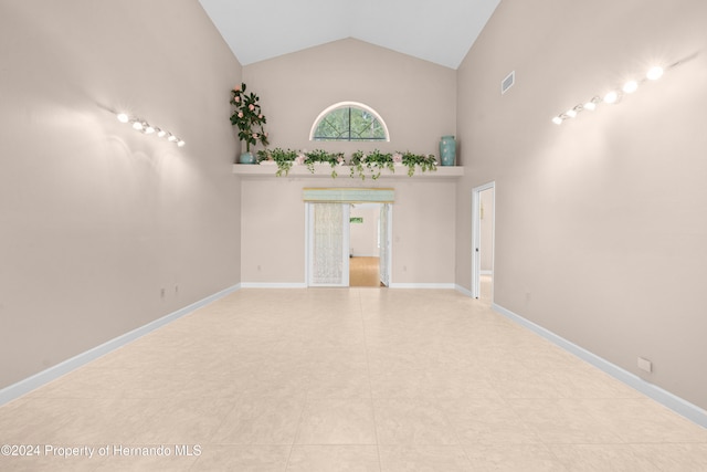 tiled spare room featuring high vaulted ceiling