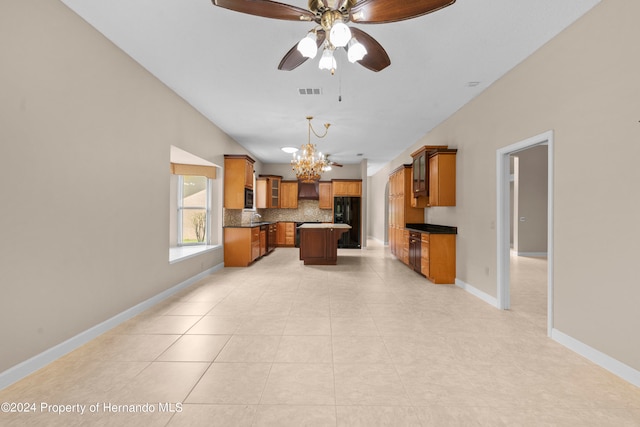 kitchen featuring ceiling fan with notable chandelier, black fridge, a center island, decorative backsplash, and hanging light fixtures