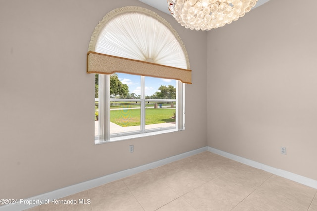 tiled empty room featuring a notable chandelier